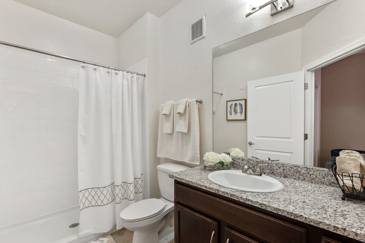 Bathroom with dark wood cabinets, silver fixtures and low entry shower