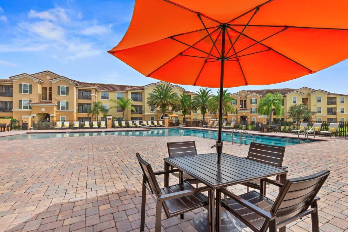 Orange umbrella with on table in pool area